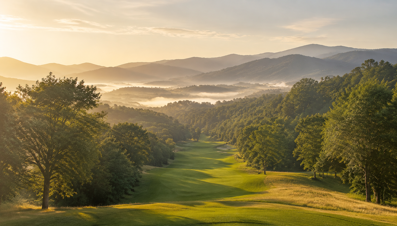 A sunlit golf fairway winding through a mountain valley